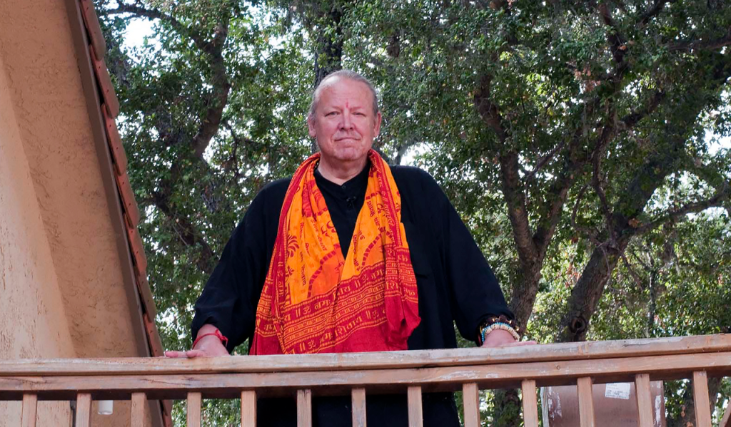 Mark Griffin stands on balcony with orange scarf.